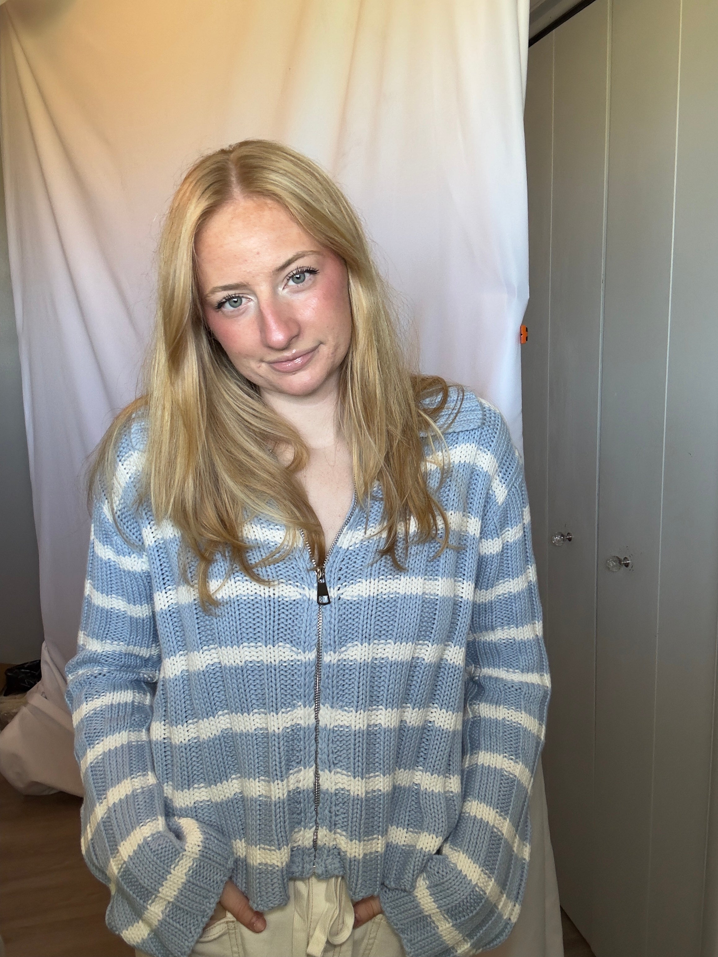 Person wearing a blue and white striped sweater in a neutral setting